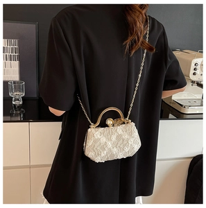 Lace floral textured evening bag with gold handle and pearl clasp on model shoulder