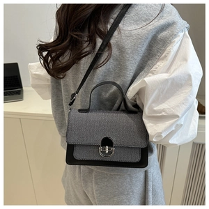 Detail of gray and black patchwork shoulder bag with silver buckle worn by a model