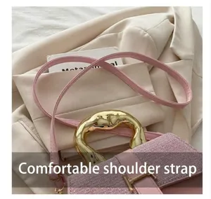 Close-up of pink crossbody bag featuring a golden H-buckle and elegant metallic handle
