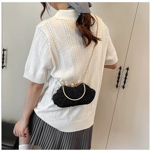 Detail of black lace clutch with pearl clasp and elegant gold handle on a white background