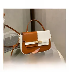 Close-up of contrast brown and white leather handbag with golden metal twist lock