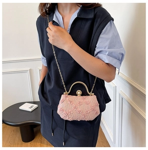 Detail of light pink lace evening bag with pearl clasp and gold chain strap