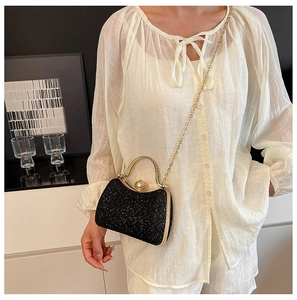 Detail of black sequined evening bag with gold handle, pearl clasp and chain strap
