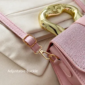 Detail of adjustable shoulder strap buckle and luxury metallic handle on pink bag