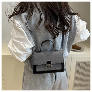 Close-up of contrast color crossbody bag featuring gray twill flap and silver metal lock