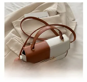 Close-up of two-tone Kelly bag featuring white scalloped stitching and gold metal lock
