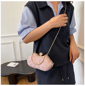 Pink lace party bag with pearl clasp and gold chain shown by model in elegant room