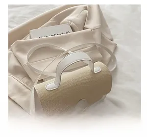 Detail shot of the woven straw flap and leather trim on this stylish beige crossbody bag