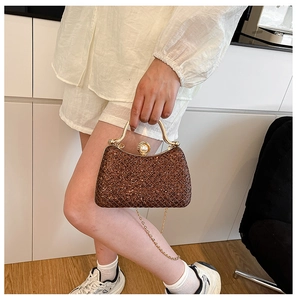 Macro view of sparkly brown sequin evening bag featuring a large pearl clasp and gold handle