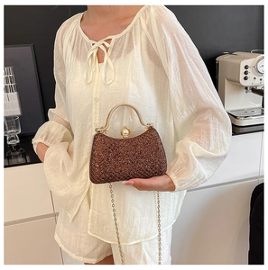 Brown glitter evening bag with gold metal handle and pearl clasp detail shown on model