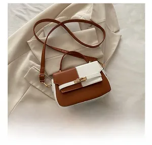 Detail show of two-tone brown and white mini handbag with gold hardware on blazer