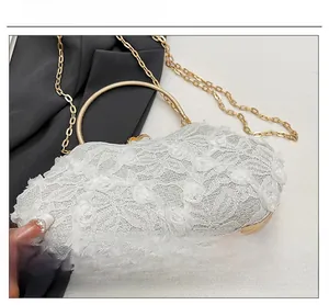 Detail of white lace evening bag featuring 3D floral textures and gold circular handle