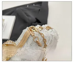 Close-up of white lace evening bag featuring a pearl rhinestone clasp and gold chain