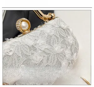 Close-up of white rose lace evening bag with gold frame and pearl rhinestone clasp