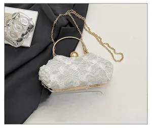 Detail of white lace evening clutch with floral patterns and gold metal top handle