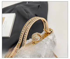 Detailed shot of white lace evening bag featuring pearl clasp and crystal wavy handles