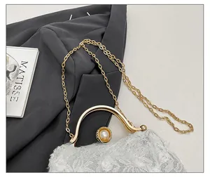 Macro detail of lace clutch bag featuring floral texture, pearl clasp and gold chain strap