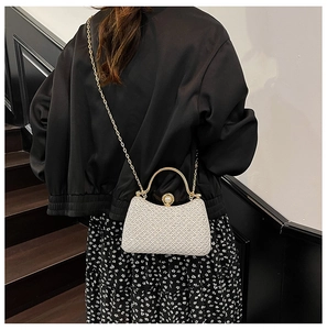Detailed shot of white lace evening clutch with golden handle and pearl clasp on shoulder