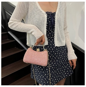 Pink rhinestone evening bag with gold handle and pearl clasp detail shown on a model
