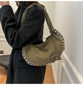 Detail van olijfgroene suède hobo tas met zilveren klinknagels en hartvormige hanger