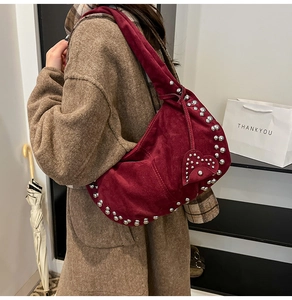 Détail du sac hobo en daim bordeaux avec rivets argentés et breloque coeur sur la bandoulière