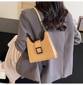 Detail of quilted leather texture and square clasp on a brown crossbody bucket bag