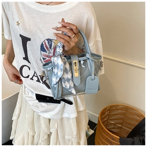 Détail d'un sac seau en PVC bleu clair avec poignée en foulard de soie et fermoir rotatif