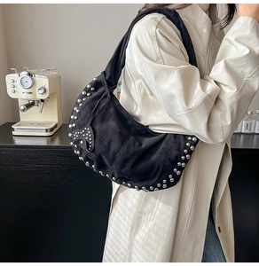 Détail du sac hobo en daim noir avec clous argentés et breloque cœur sur la bandoulière