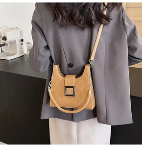 Brown quilted bucket bag with adjustable strap worn by a model in a cafe setting