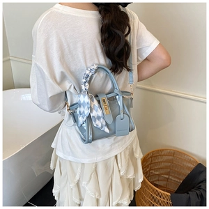 Model view of a light blue mini bucket bag featuring a silk scarf handle and golden lock