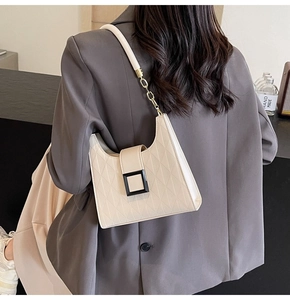 Detail of cream white tote bag with quilted texture and decorative black resin buckle