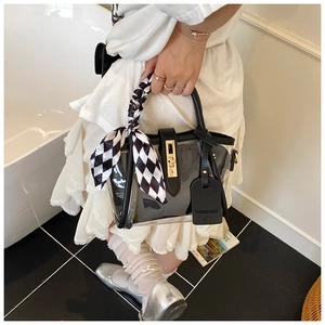 Détail du sac seau en PVC transparent avec fermoir doré et anse en foulard damier