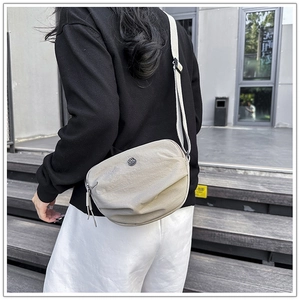 Close-up of a crescent-shaped nylon crossbody bag with adjustable strap and metal logo