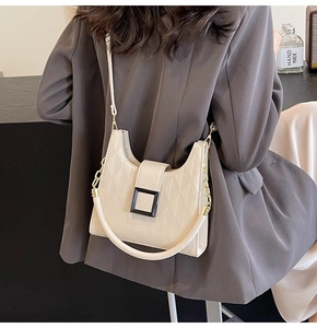 Detail of off-white quilted tote bag showing black square buckle and versatile strap design