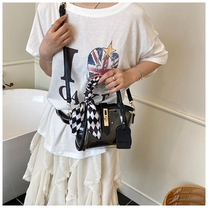 Detailed view of clear PVC bucket bag with black leather trim and decorative silk scarf