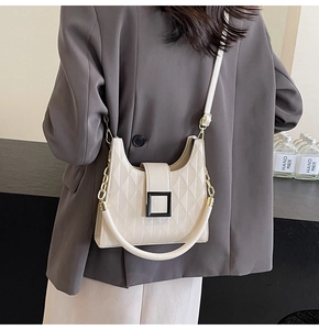 Detail of quilted diamond pattern and square buckle on cream crossbody bucket bag