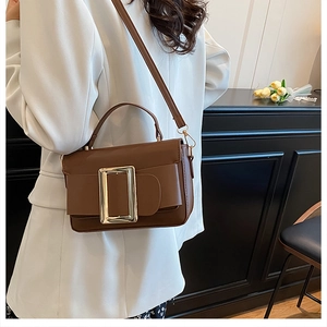 Close-up of brown matte leather crossbody bag with a large golden buckle accessory