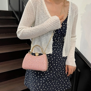 Pink rhinestone evening bag with gold handle and chain strap worn by a woman