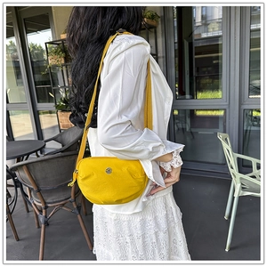 Detail of yellow nylon crossbody bag with crescent shape and adjustable shoulder strap