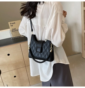 Close-up of black quilted shoulder bag featuring geometric textures and metal chain strap