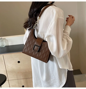 Close-up of a dark brown quilted bucket bag with a retro square clasp and chain strap
