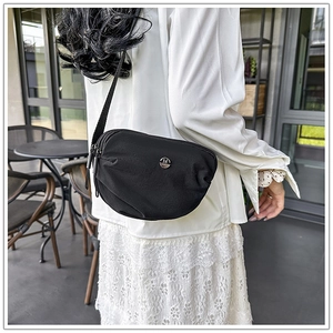 Detail of black nylon crossbody bag with silver M logo and adjustable shoulder strap