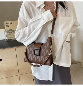 Detail of dark brown quilted crossbody bucket bag with square buckle and leather handle
