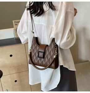 Detail of a brown quilted tote bag with a black square buckle and dual strap design