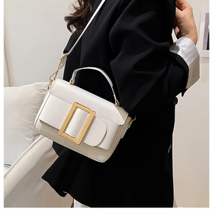 Detail of white leather crossbody bag with a prominent gold square metal buckle on black blazer