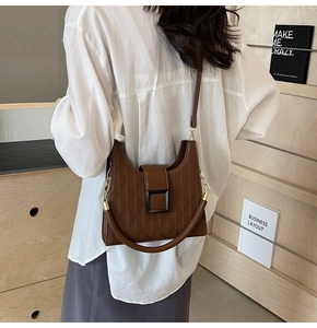 Detailed view of brown quilted leather bucket bag with square buckle and chain strap