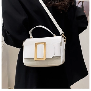 White faux leather crossbody bag with elegant gold clasp on a black blazer jacket