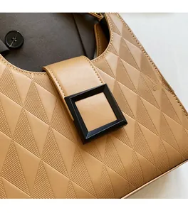 Detail of tan quilted leather texture and black square buckle on a stylish bucket bag