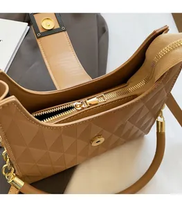 Detail of camel quilted bucket bag showing gold zipper hardware and interior pocket