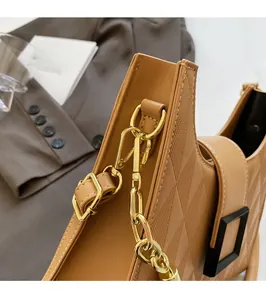 Detail of caramel quilted tote bag with golden metal chain strap and luxury texture
